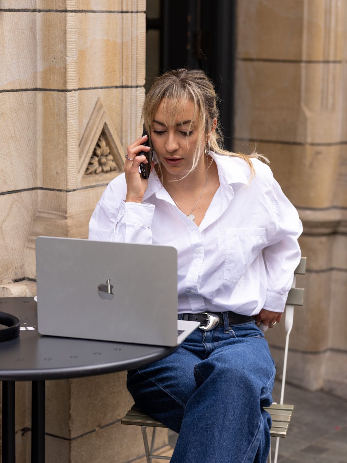 Beth Norton working on a laptop outside a stone building